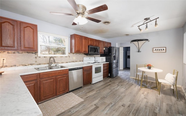 kitchen featuring backsplash, sink, stainless steel appliances, and light hardwood / wood-style flooring