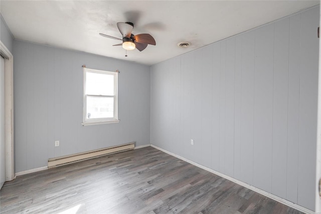 spare room with baseboard heating, ceiling fan, hardwood / wood-style floors, and wood walls