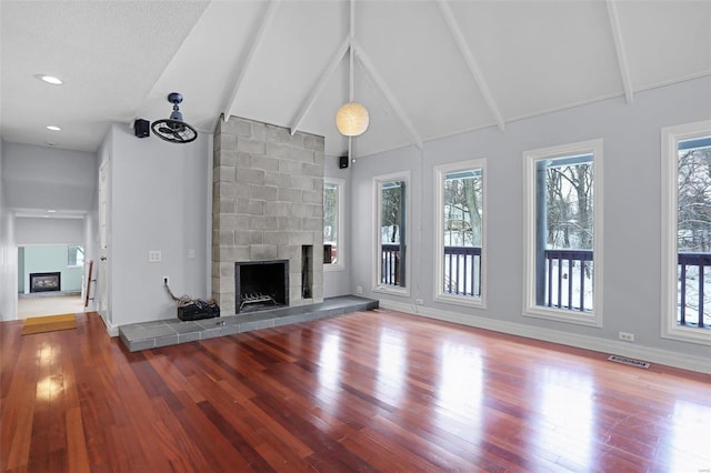 unfurnished living room with a fireplace, hardwood / wood-style floors, and vaulted ceiling with beams