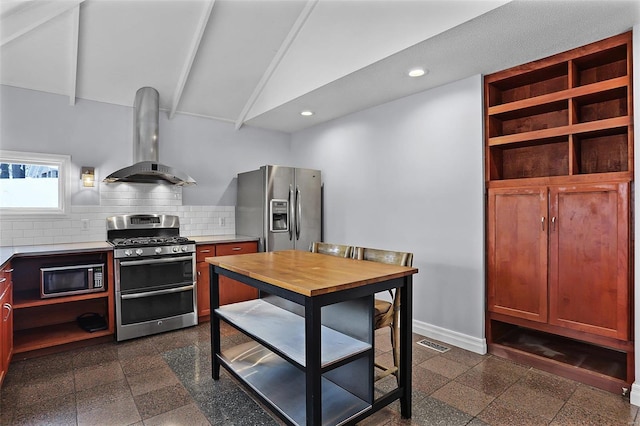 kitchen with lofted ceiling, wall chimney exhaust hood, tasteful backsplash, and appliances with stainless steel finishes