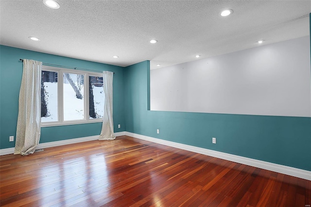 unfurnished room with wood-type flooring and a textured ceiling