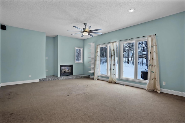 unfurnished living room with a textured ceiling, ceiling fan, a wealth of natural light, and carpet