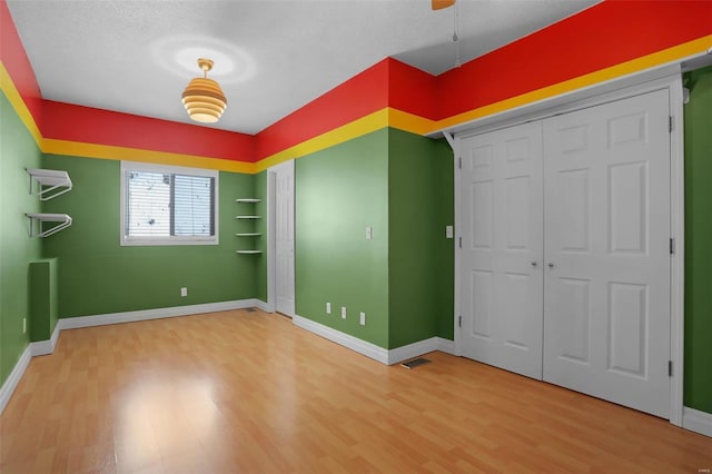 unfurnished bedroom featuring a textured ceiling, a closet, and hardwood / wood-style floors