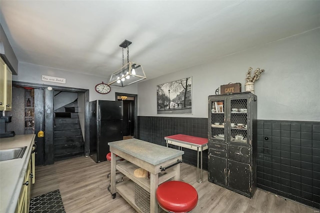 dining space featuring light hardwood / wood-style floors, tile walls, and sink