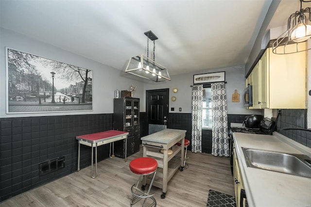 kitchen featuring light hardwood / wood-style floors, sink, stainless steel appliances, and tile walls