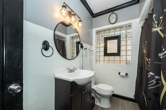 bathroom featuring hardwood / wood-style floors, vanity, toilet, ornamental molding, and tile walls