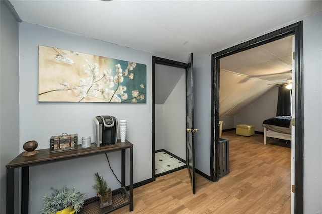 hall with vaulted ceiling and light hardwood / wood-style flooring