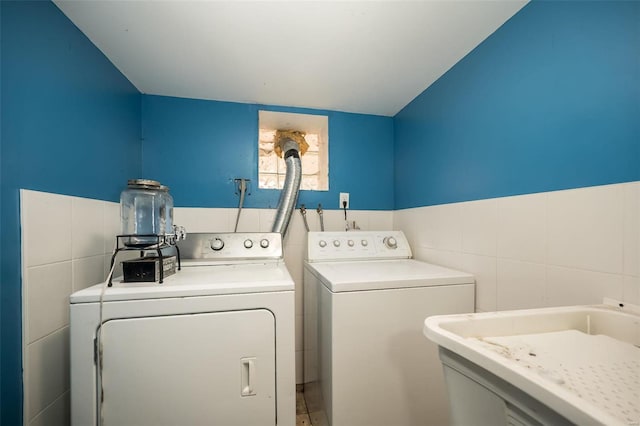 laundry room featuring washing machine and dryer, tile walls, and sink