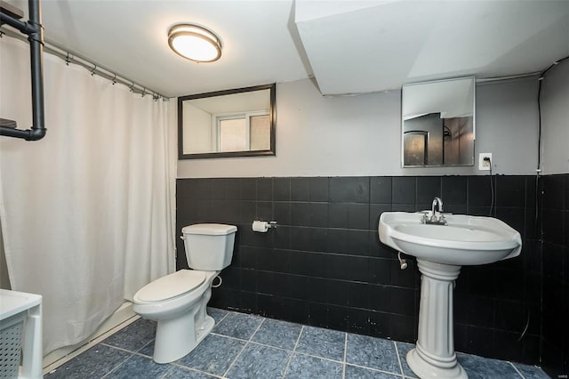 bathroom featuring a shower with shower curtain, toilet, and tile walls