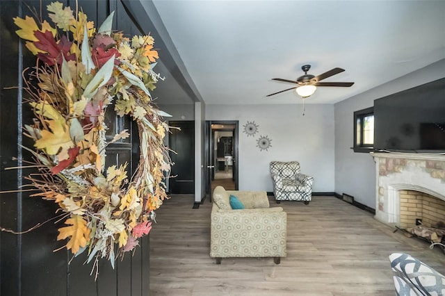 living area with ceiling fan, baseboards, wood finished floors, and a high end fireplace