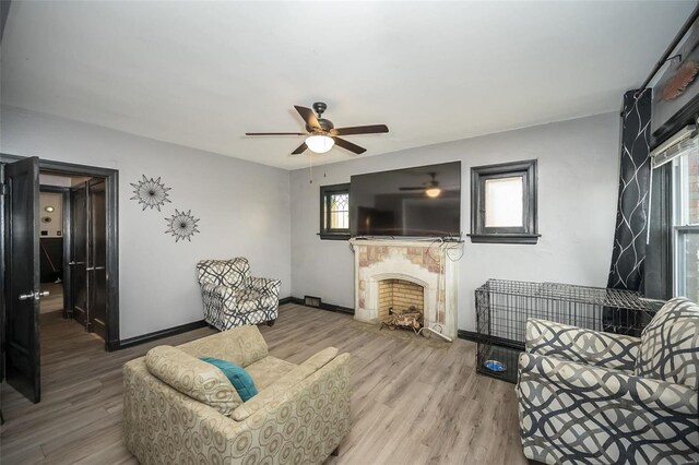 living area with light wood-style floors, a ceiling fan, baseboards, and a premium fireplace