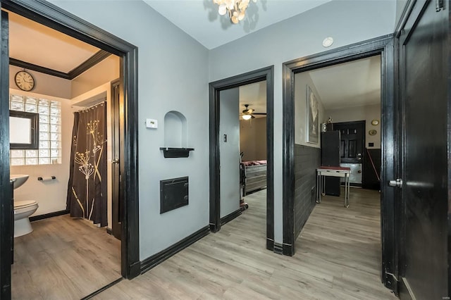 hallway with light wood-style flooring, baseboards, and ornamental molding