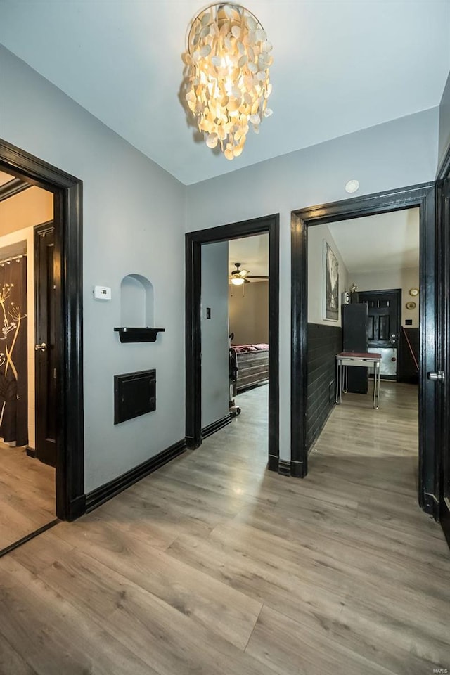 hall featuring light wood-type flooring and an inviting chandelier