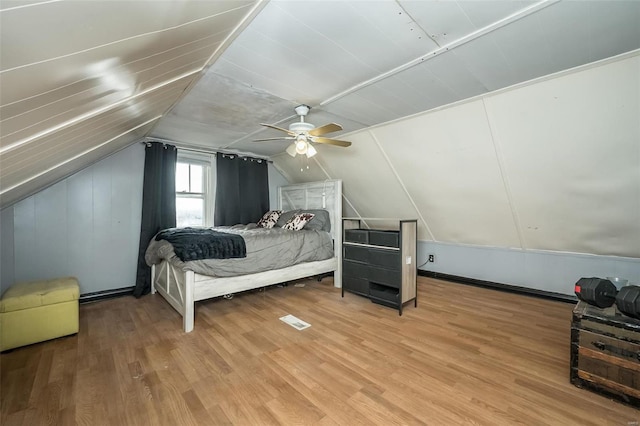 bedroom with light wood finished floors, visible vents, vaulted ceiling, and a ceiling fan