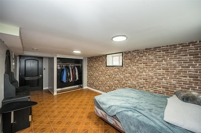 bedroom with brick wall, baseboards, and a closet