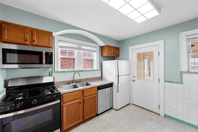 kitchen featuring sink, tile walls, and appliances with stainless steel finishes