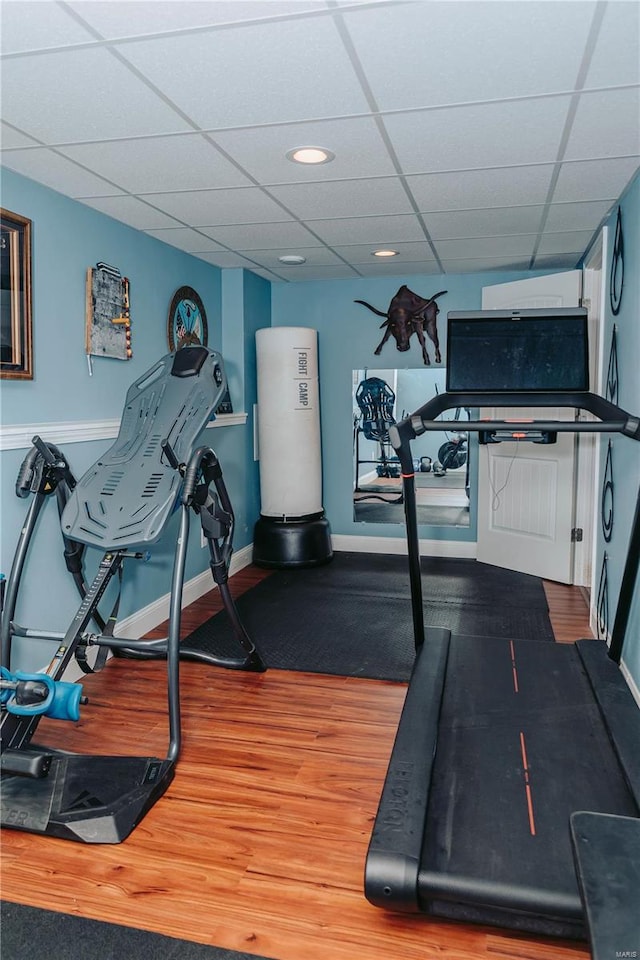 exercise room with a paneled ceiling and wood-type flooring