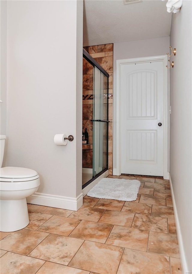 bathroom with a shower with door and toilet