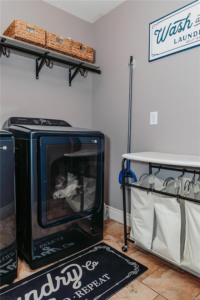 clothes washing area featuring washing machine and clothes dryer and tile patterned floors