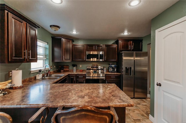 kitchen with sink, a breakfast bar area, dark brown cabinets, stainless steel appliances, and kitchen peninsula