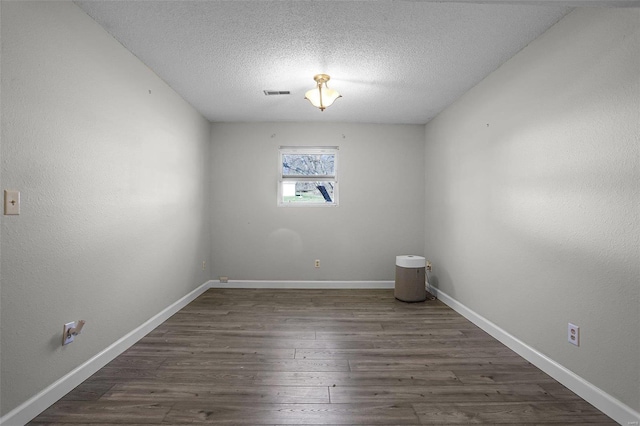 spare room featuring a textured ceiling and dark hardwood / wood-style floors