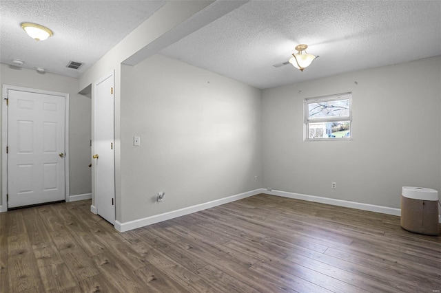 unfurnished room with hardwood / wood-style flooring and a textured ceiling