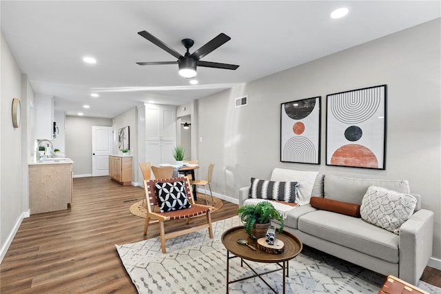 living room featuring hardwood / wood-style flooring, ceiling fan, and sink