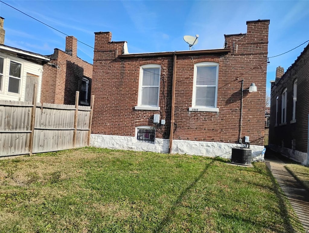 rear view of property featuring a yard and central AC unit