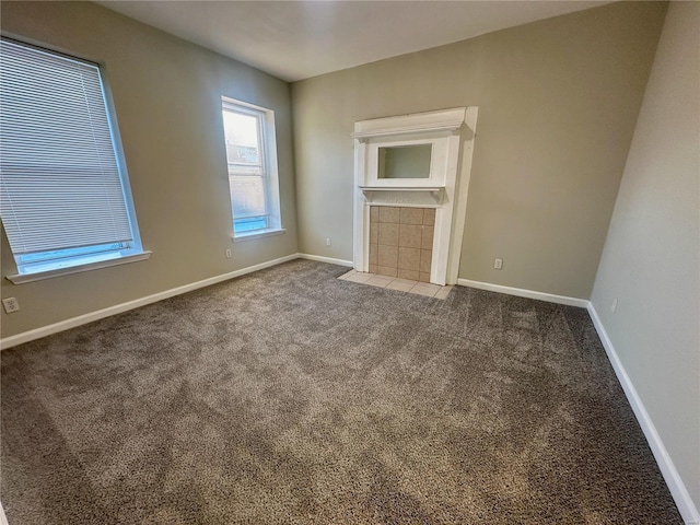 unfurnished living room featuring dark colored carpet and a tiled fireplace