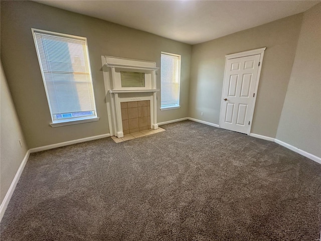 unfurnished living room featuring a tile fireplace and dark carpet