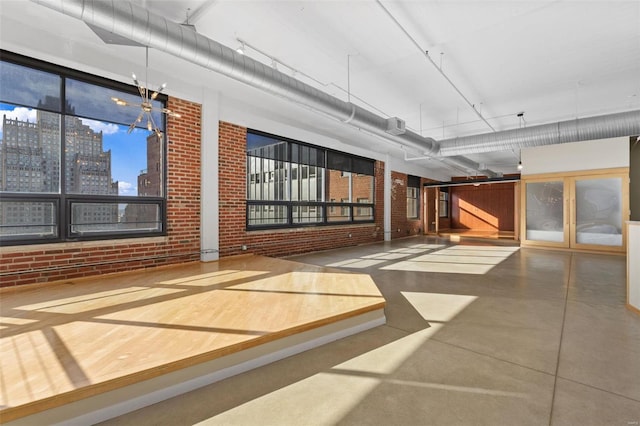 interior space featuring a towering ceiling, brick wall, and concrete floors