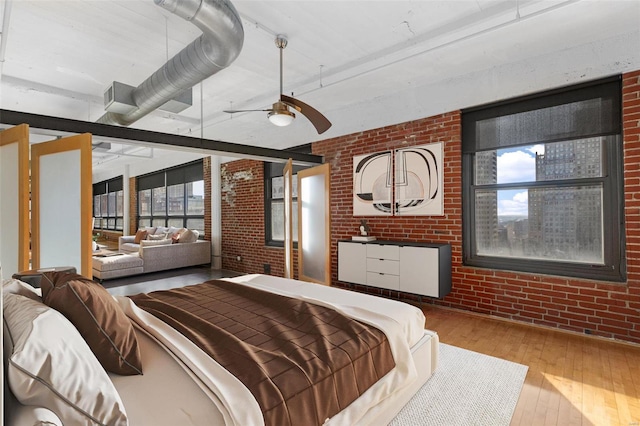 bedroom with ceiling fan, brick wall, and light wood-type flooring