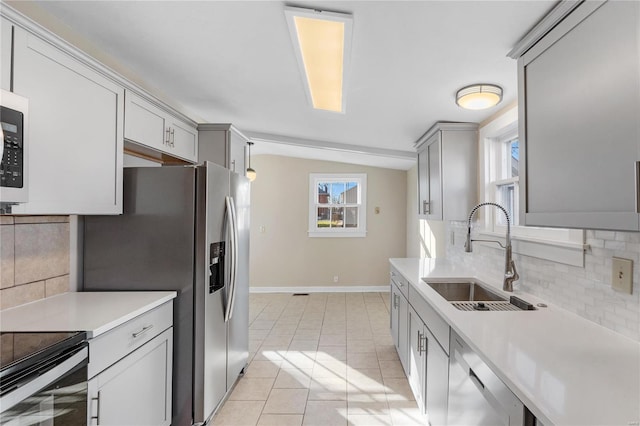 kitchen featuring appliances with stainless steel finishes, backsplash, sink, gray cabinets, and light tile patterned flooring