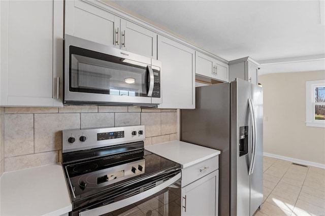 kitchen featuring white cabinets, decorative backsplash, light tile patterned floors, and appliances with stainless steel finishes