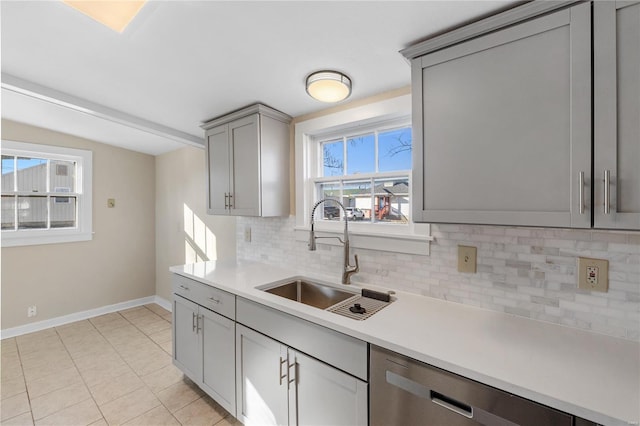 kitchen featuring backsplash, stainless steel dishwasher, sink, gray cabinets, and light tile patterned flooring