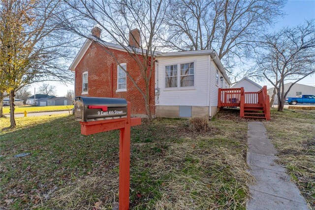 view of property exterior with a lawn and a wooden deck