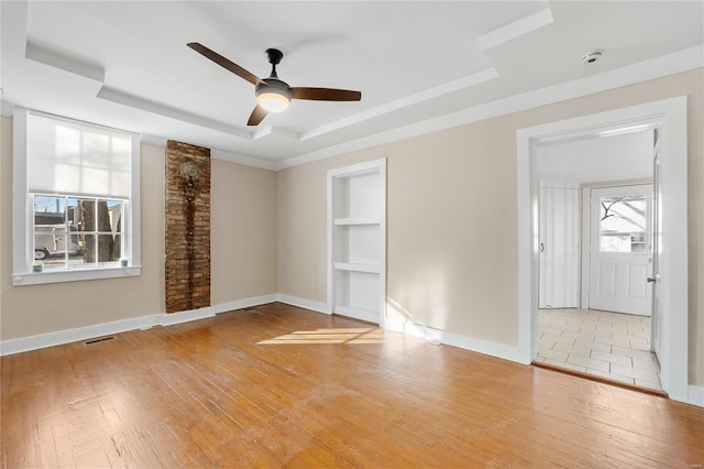 unfurnished room featuring ceiling fan, a healthy amount of sunlight, wood-type flooring, and built in features