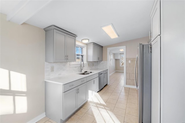 kitchen with appliances with stainless steel finishes, gray cabinets, light tile patterned floors, and sink