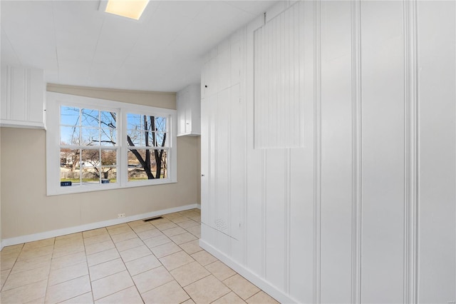 unfurnished room with light tile patterned flooring and vaulted ceiling