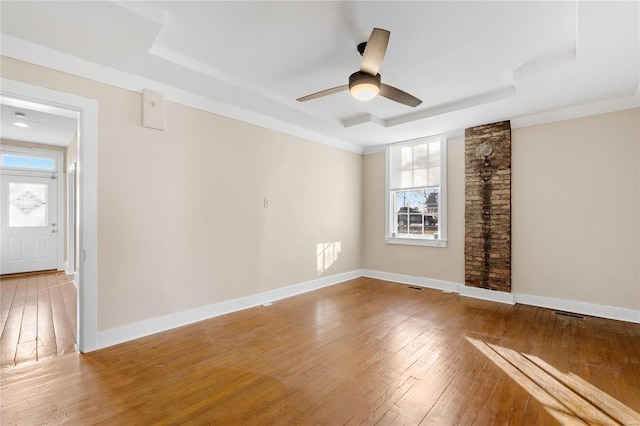 empty room featuring a tray ceiling, ceiling fan, and hardwood / wood-style flooring