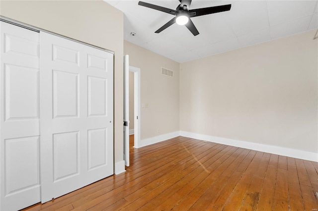 unfurnished bedroom featuring a closet, hardwood / wood-style flooring, and ceiling fan