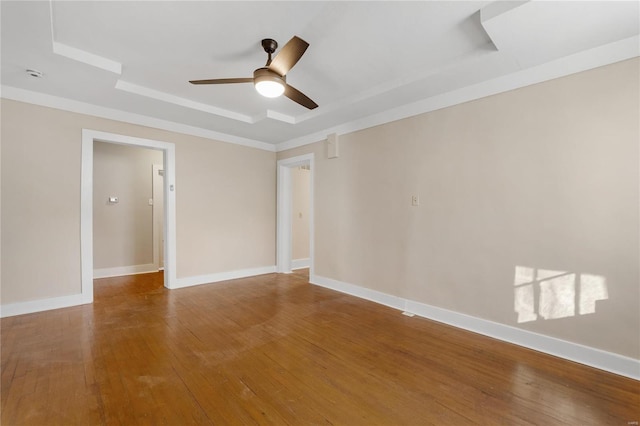 empty room featuring a raised ceiling, ceiling fan, and hardwood / wood-style flooring