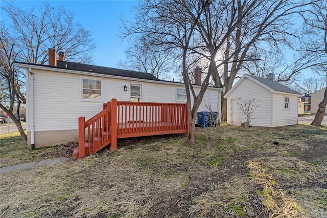 back of property featuring an outbuilding, a deck, and a garage