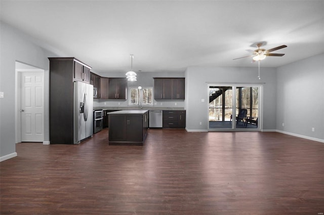 kitchen featuring hanging light fixtures, a kitchen island, dark brown cabinetry, dark hardwood / wood-style flooring, and stainless steel appliances