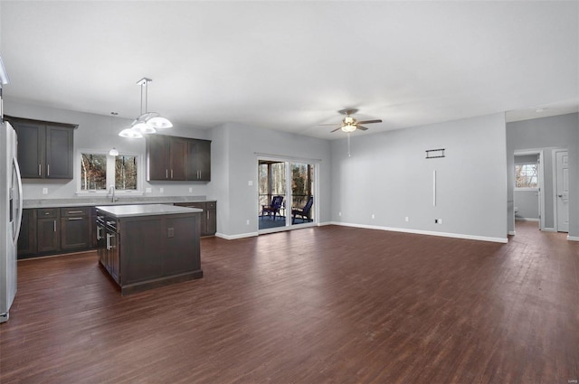 kitchen featuring dark brown cabinetry, a center island, a healthy amount of sunlight, and dark hardwood / wood-style floors