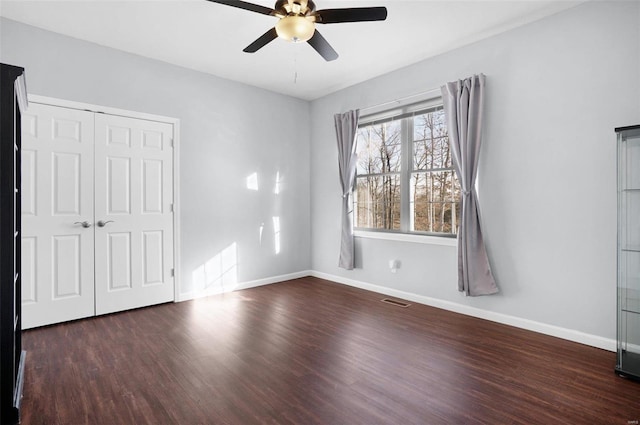 unfurnished bedroom with dark wood-type flooring, a closet, and ceiling fan