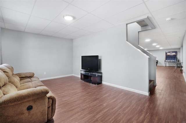 living room featuring dark wood-type flooring and a paneled ceiling