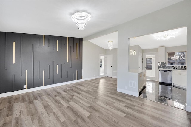 unfurnished living room featuring ceiling fan with notable chandelier, vaulted ceiling, and light hardwood / wood-style flooring