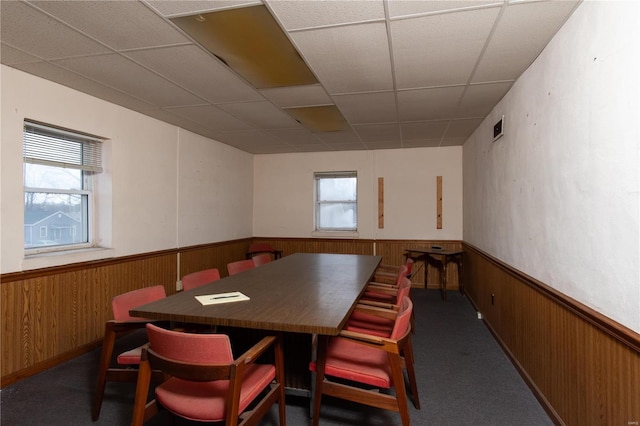 carpeted dining area with a paneled ceiling