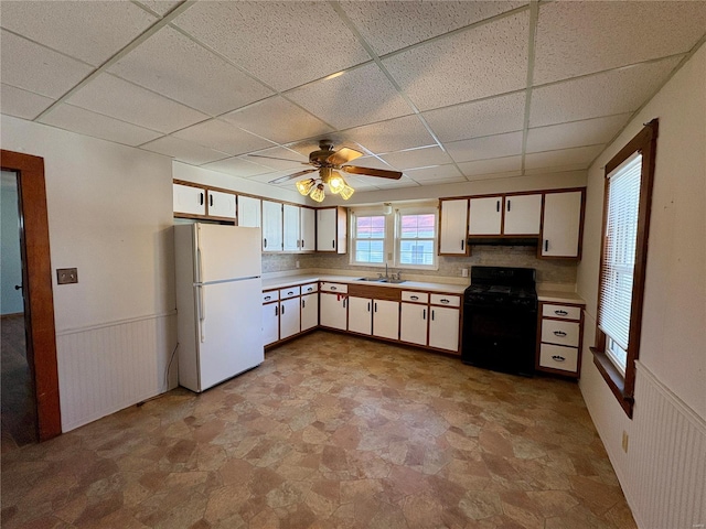 kitchen featuring white cabinets, black stove, white fridge, and sink